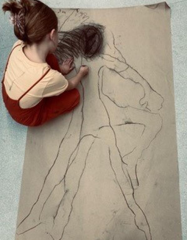 Girl drawing a figure on large format paper 
