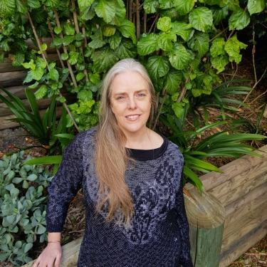 A woman in a black and silver top standing in a garden