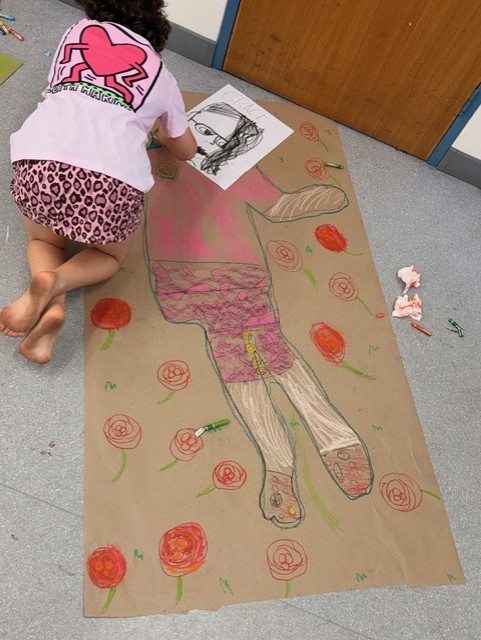 Girl drawing on a large piece of brown paper on the floor