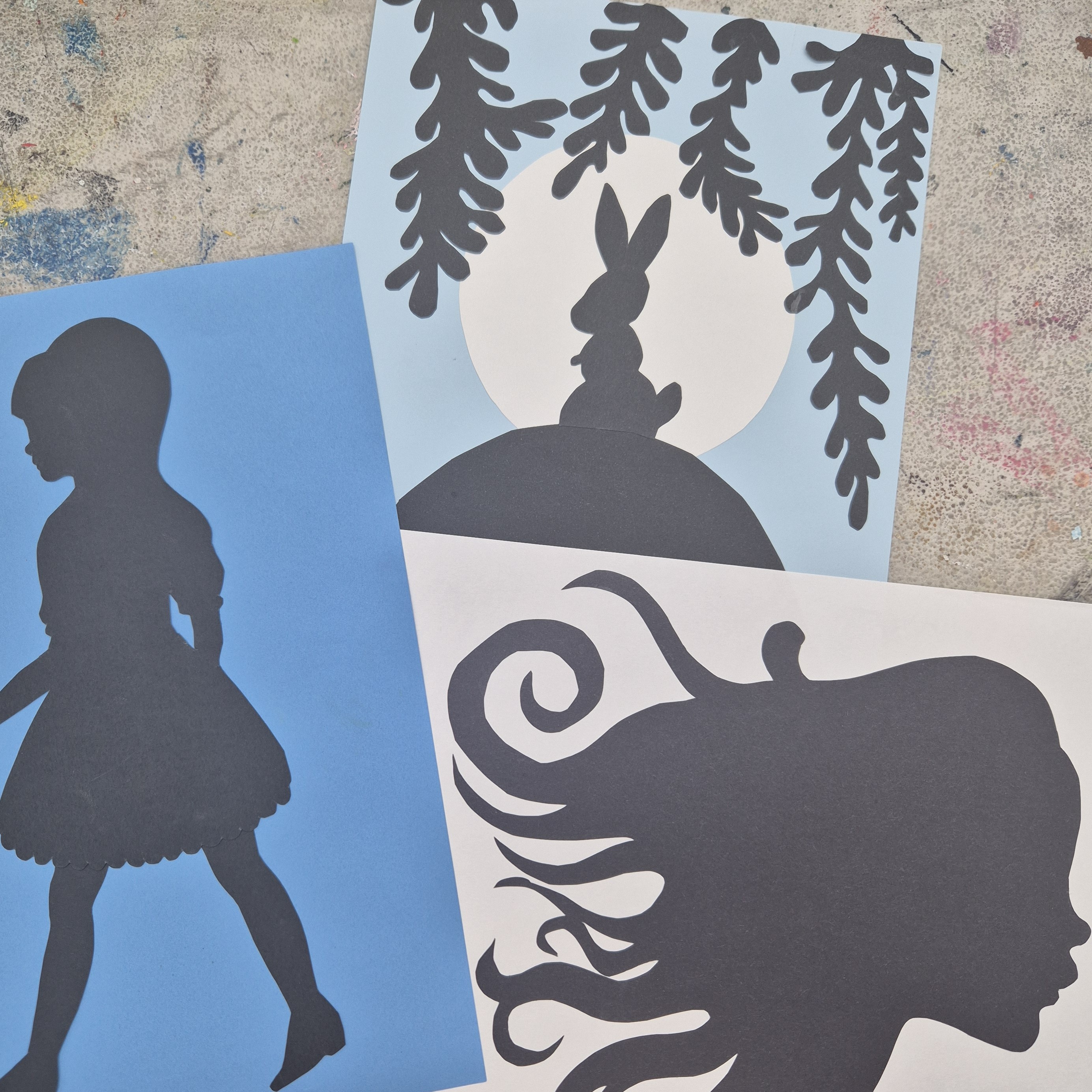 Black silhouettes of a girl, a side profile with flowing hair & a rabbit.