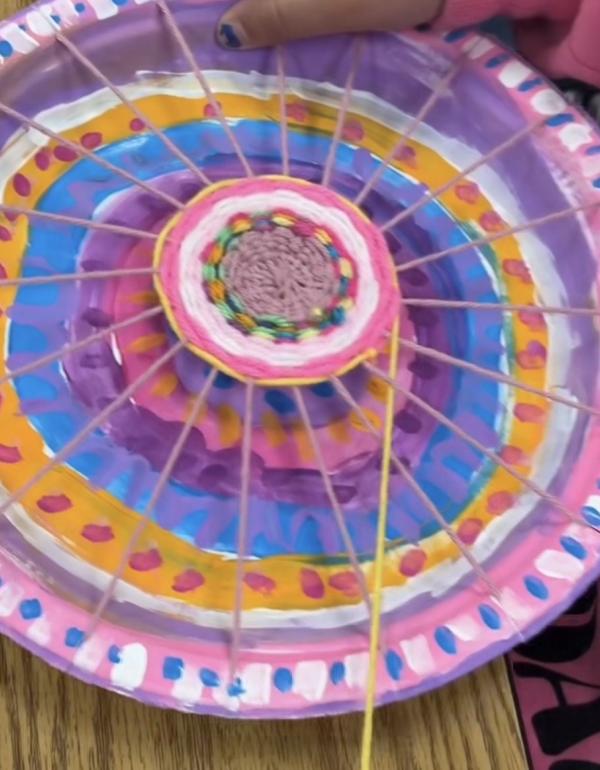 Paper plate with wool woven across it 