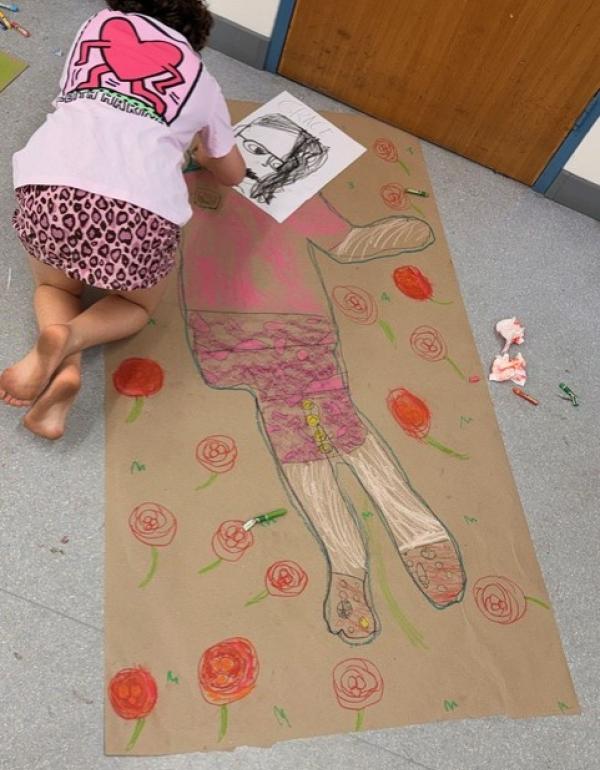 Girl drawing on a large piece of brown paper on the floor