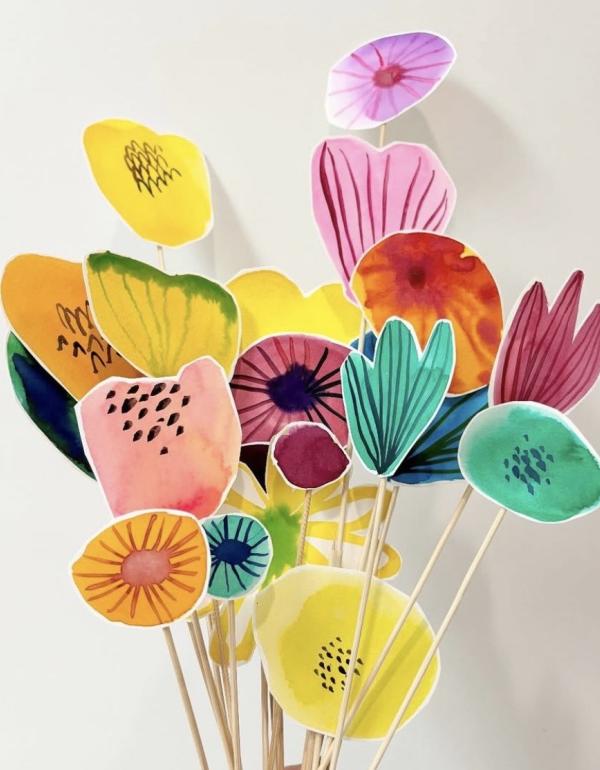 Multiple bright coloured painted flowers, all on sticks.